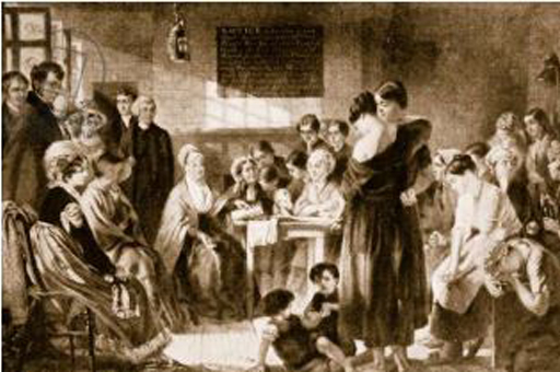 This is a black and white image of a well-dressed older woman seated at a central table in a crowded room. She reads aloud to a group of women on the right: some are seated, while two stand supporting each other in the foreground, with children at their feet. A group of visitors observe the scene from the left.
