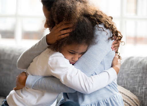 This is a photograph of a child being hugged by an adult.
