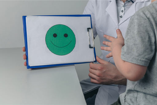 This is a photograph of a therapist holding a clipboard with a drawing of a smiley face on it.