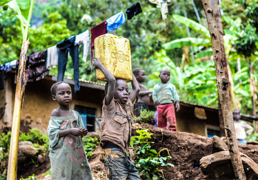 This is a photograph of two young children, with one carrying a container of water on their head.