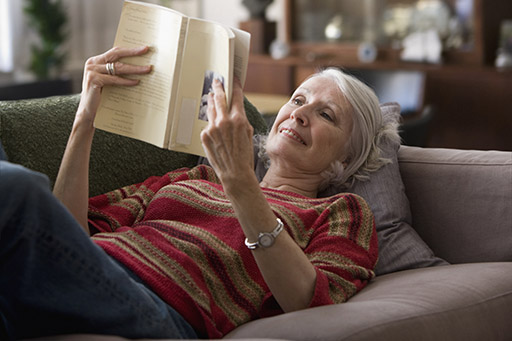 This image shows a person laying back on a sofa reading a book.
