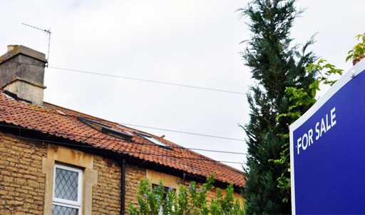 This is a photo of a house with a ‘For Sale’ sign outside.
