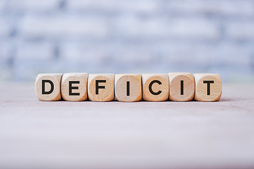 The figure shows seven dice in a row, each with a letter displayed. Collectively the letters make the word ‘deficit’.