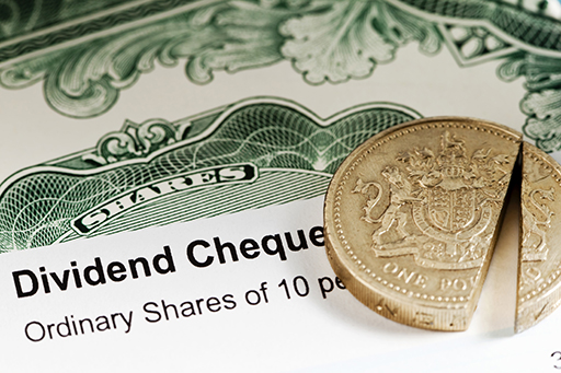 The figure shows a cheque for a share dividend. On top of the cheque is a one-pound coin split into two parts.