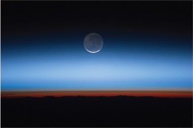 This photograph shows the Earth and moon taken from the International Space Station. The view looks out over the Earth, with the troposphere as the horizon (in red-brown). Above that is the stratosphere, but the stratosphere is not clearly delineated from space. The moon is seen in the centre of the image, appearing above the horizon.