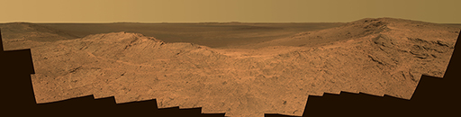 This figure is a panoramic photograph taken by the Opportunity rover of the martian surface. A ridge is evident, lying left to right across the image. This is coloured light orange. Behind this is a darker orange region that appears flat. The horizon in the distance is horizontal and the sky is pale yellow.