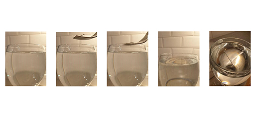 This image shows five photographs that illustrate the steps in Activity 2. From left to right, the first photograph shows a clean glass filled with water. The next two photographs show a fork with a needle balanced on it being lowered onto the water in the glass. The fourth photograph shows the needle floating on the water surface – the fork has been removed from the image. The final image shows an aerial view of the surface of the water, with the needle floating. ‘Dents’ in the water are visible around the needle.