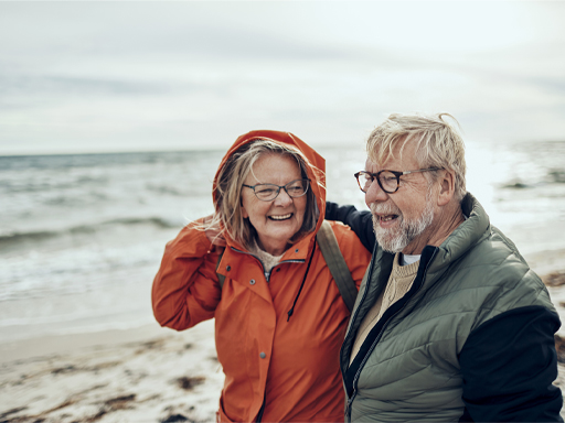 The figure is a photo showing an elderly couple in anoraks walking on the beach.