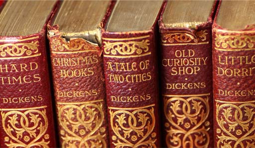 This is a colour photograph of five books bound in red leather. Their titles are tooled in gold on the spines, and include Hard Times, A Tale of Two Cities, and Little Dorrit.