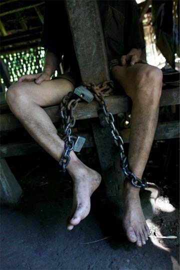 A photograph of a young man chained to a poll.