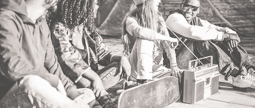 A black and white image of four prople sat on the floor talking to eachother.