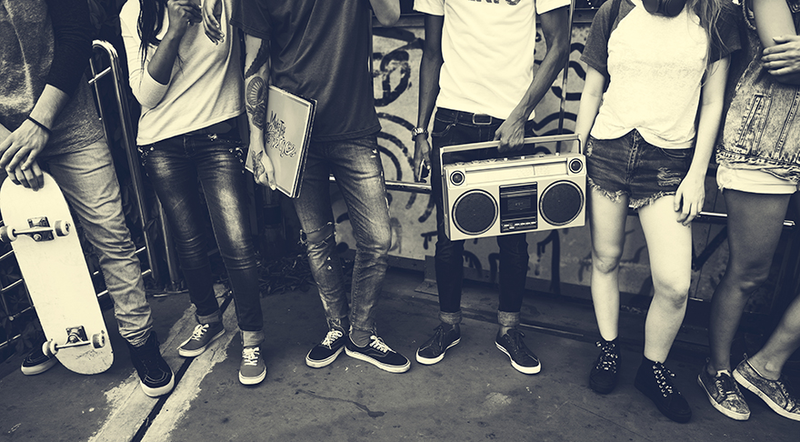 This is a black and white image of 6 people standing against a wall, their heads are cropped out.