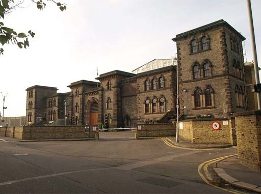 This is a colour photograph of the frontage of a stone-built prison. It is flanked by two square four-storey towers, with smaller towers framing a central archway.