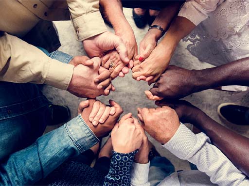 A photograph of multiple hands paired up and forming a circle.