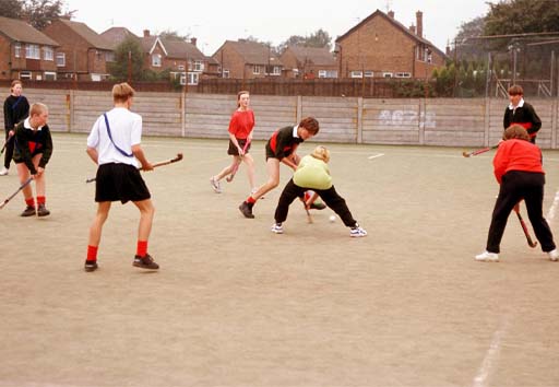 A photograph of young people playing hockey.
