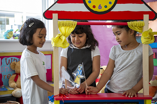 Three children playing in the classroom play area.