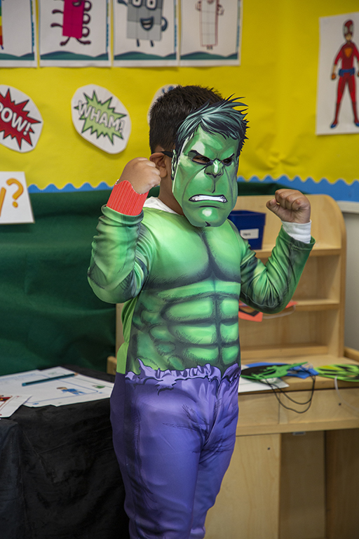A child dressed up in a Hulk outfit and mask.
