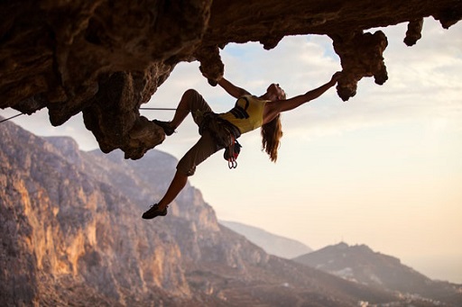Image of a female rock climber scaling an overhang in a mountain location