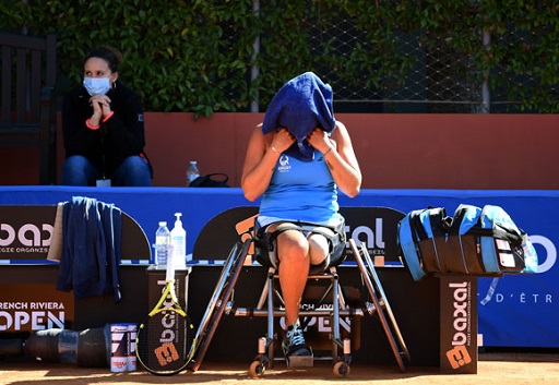 Image of female wheelchair athlete on courtside during a break in play with towel over her head