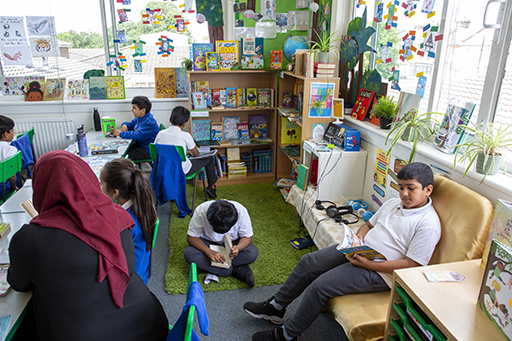 School children sat in a classroom reading environment reading individually.