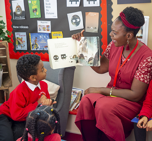 An adult reading aloud to a school child who is looking on intently.