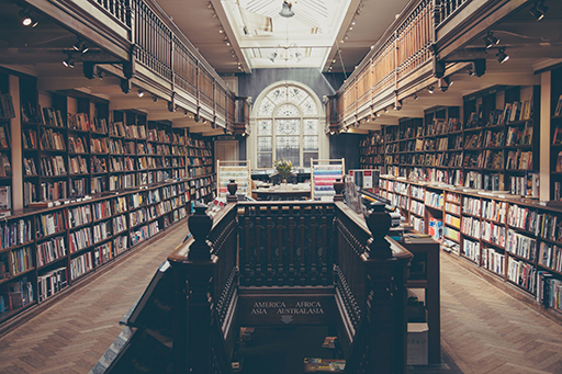 A photo of a library with a window and stairs with bookcases either side.