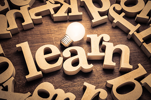 Wooden letter spelling the word ‘learn’ next to a lit light bulb.