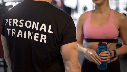 The image shows the back of a personal trainer and the front of their client. We only see them from the neck down to the waist but they are facing each other.