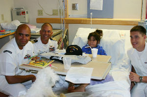 From left, Information Systems Technician 1st Class Tyrel Maynor, USS Cleveland (LPD 7) Commanding Officer Capt. Frank McCulloch, and Culinary Specialist Seaman Sean Unterdorfer visit a patient at Cleveland's Rainbow Babies and Children's Hospital. 