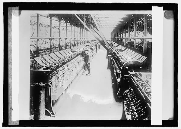Old black-and-white photograph showing rows of machine looms in a linen mill.