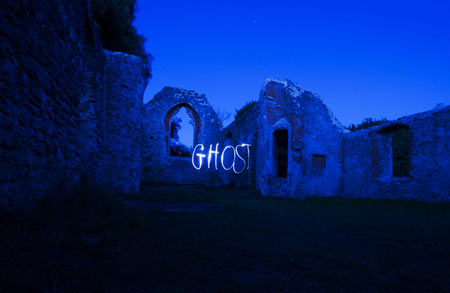 The word ghost written in light against a ruin