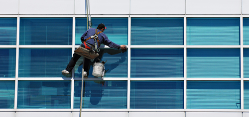 A window cleaner hanging off the side of a building