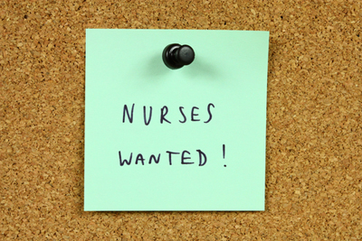 Green sticky note pinned to an office notice board. Nurses wanted - medical career opportunity and recruitment information.