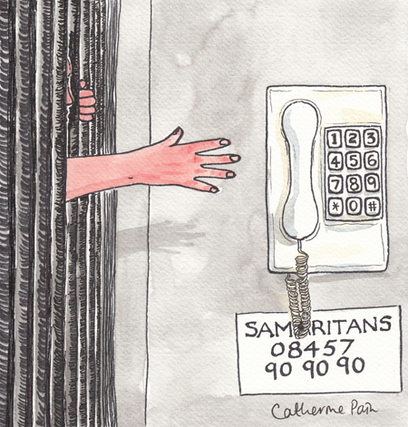 A person behind a black curtain reaches out for a telephone on the wall above a sign for the Samaritans.