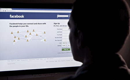 Facebook interface on a computer with a man sitting infront