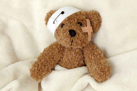 teddy bear ill in bed with a bandaged ear
