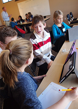 Group of junior school children working together around a tablet computer