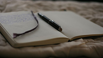 A journal with writing in and a pen on top