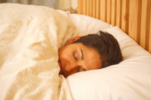 A woman snuggled in bed, fast asleep