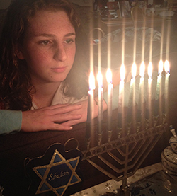 Girl looking at menorah with lit candles