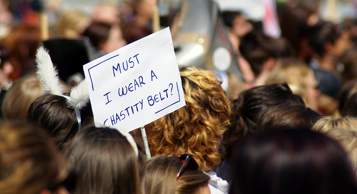 Must I Wear a Chastity Belt? sign with protestors