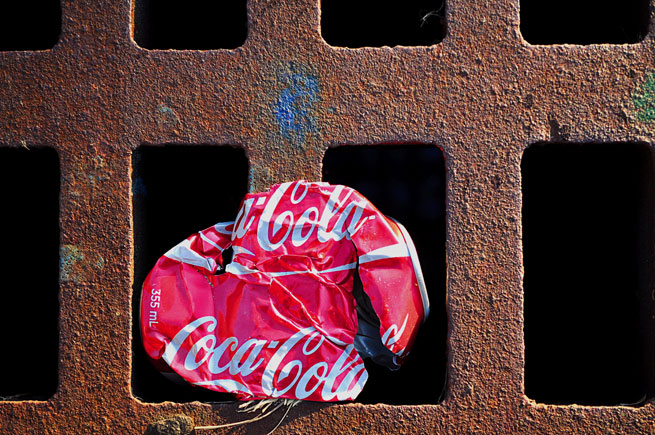 A crushed coke can caught on a drain
