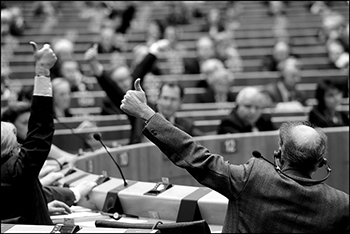Members of the European Parliament voting on a resolution during Brussels plenary session - black and white image showing men with their thumbs in the air. 