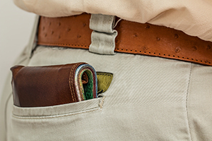 Pair of beige trousers with a wallet in the back pocket containing money