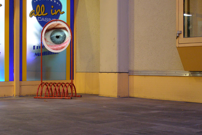 Watching you: a giant picture of an eye on a stand above a bicycle rack