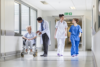 doctors and nurses in a corridor with a patient in a wheelchair