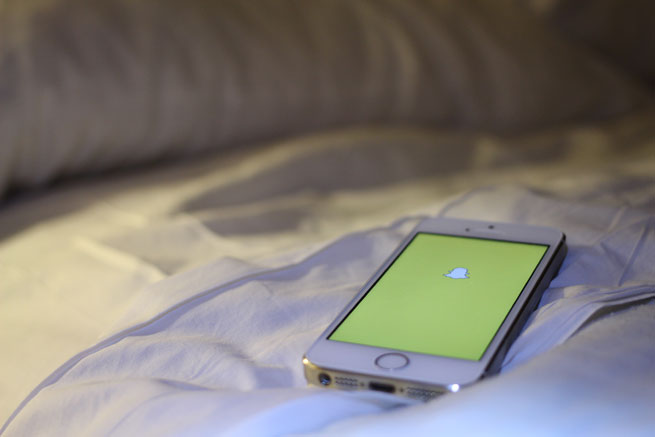 Snapchat logo on a phone on a bed