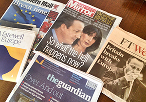 5 newspapers lay on a table, with the headlines 'Britain breaks with Europe', 'over and out', 'So what the hell happens now?' and 'Brexit time'. Images of David Cameron looking shocked on the front pages.