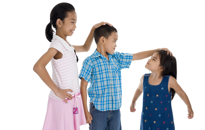 Three children comparing heights