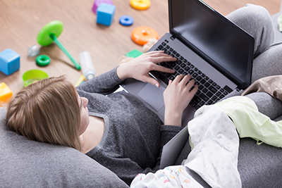 student parent on a laptop with toys surrounding her